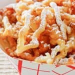 closeup of funnel cake fries in a paper serving dish