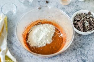 adding flour to chocolate mixture in a bowl