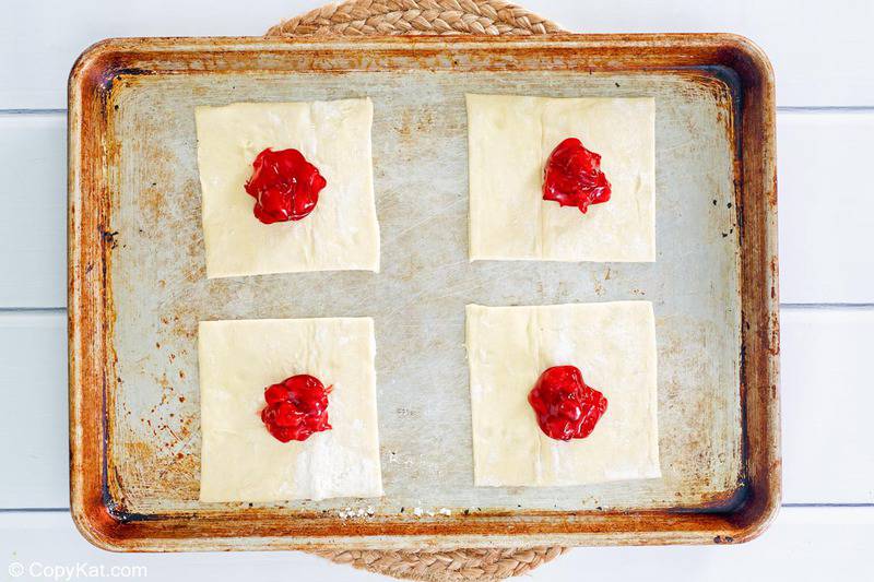 puff pastry square with cherry pie filling in the center of each one
