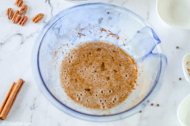spiced pecans coating mixture in a bowl