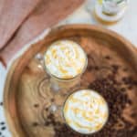 overhead view of two caramel macchiato coffee drinks and a bottle of vanilla syrup