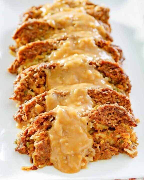 sliced of stuffed meatloaf with gravy on a platter