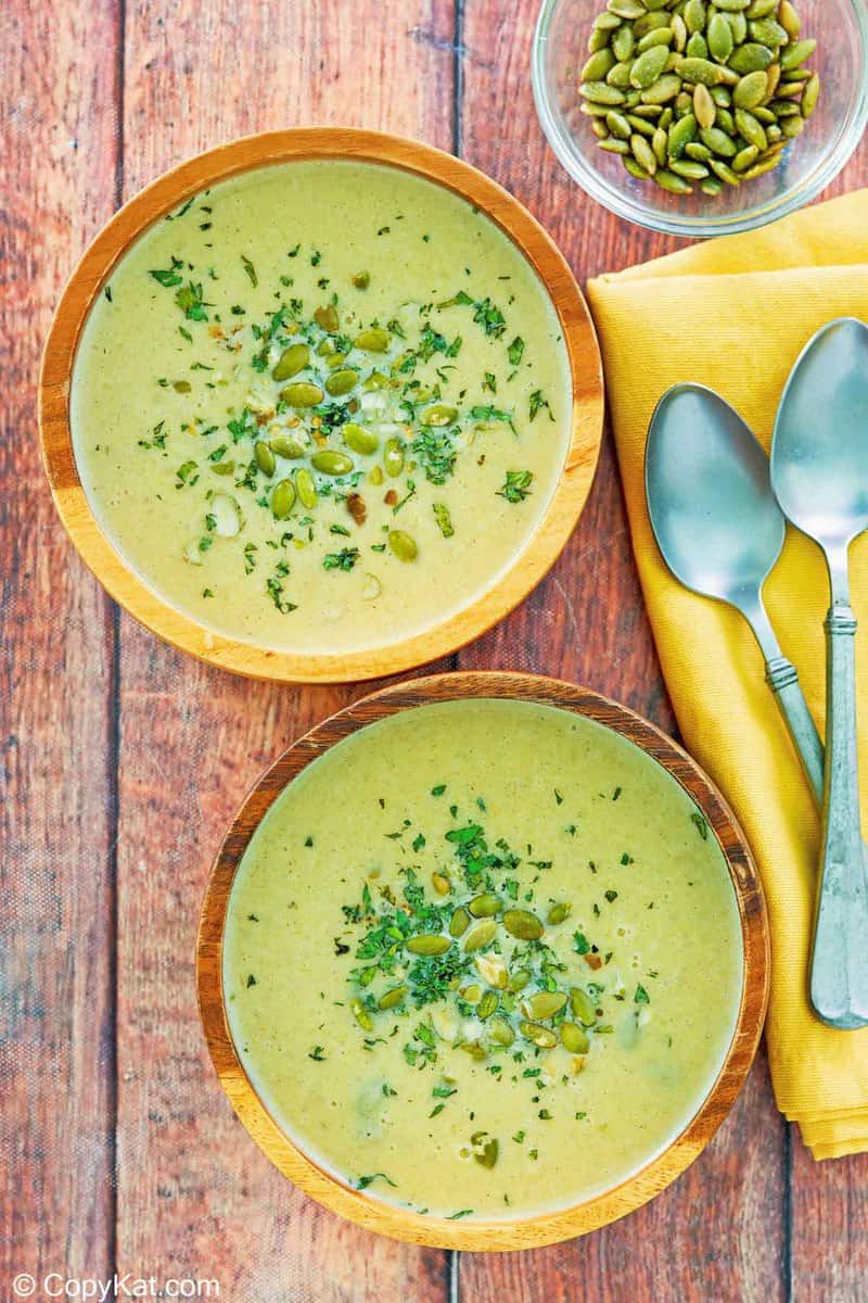 overhead view of two bowls of acorn squash soup and a bowl of pumpkin seeds.