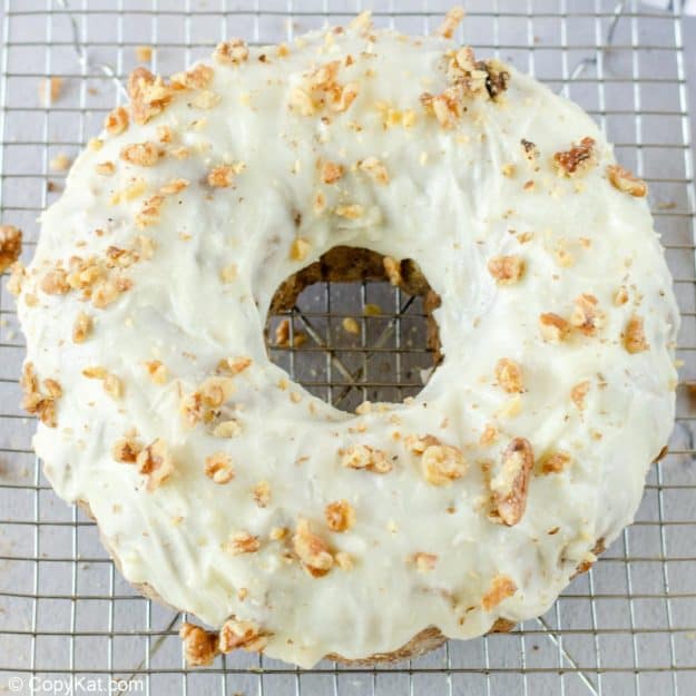 apple spice cake with cream cheese frosting topped with chopped walnuts.
