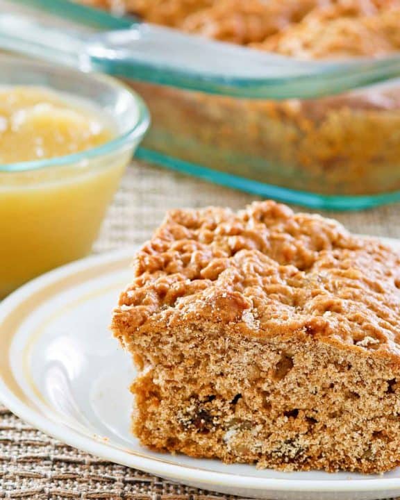 a slice of applesauce cake on a plate and applesauce in a small bowl.
