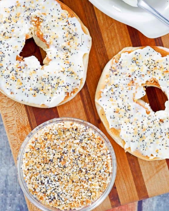 a bowl of homemade everything bagel seasoning and a bagel with cream cheese.