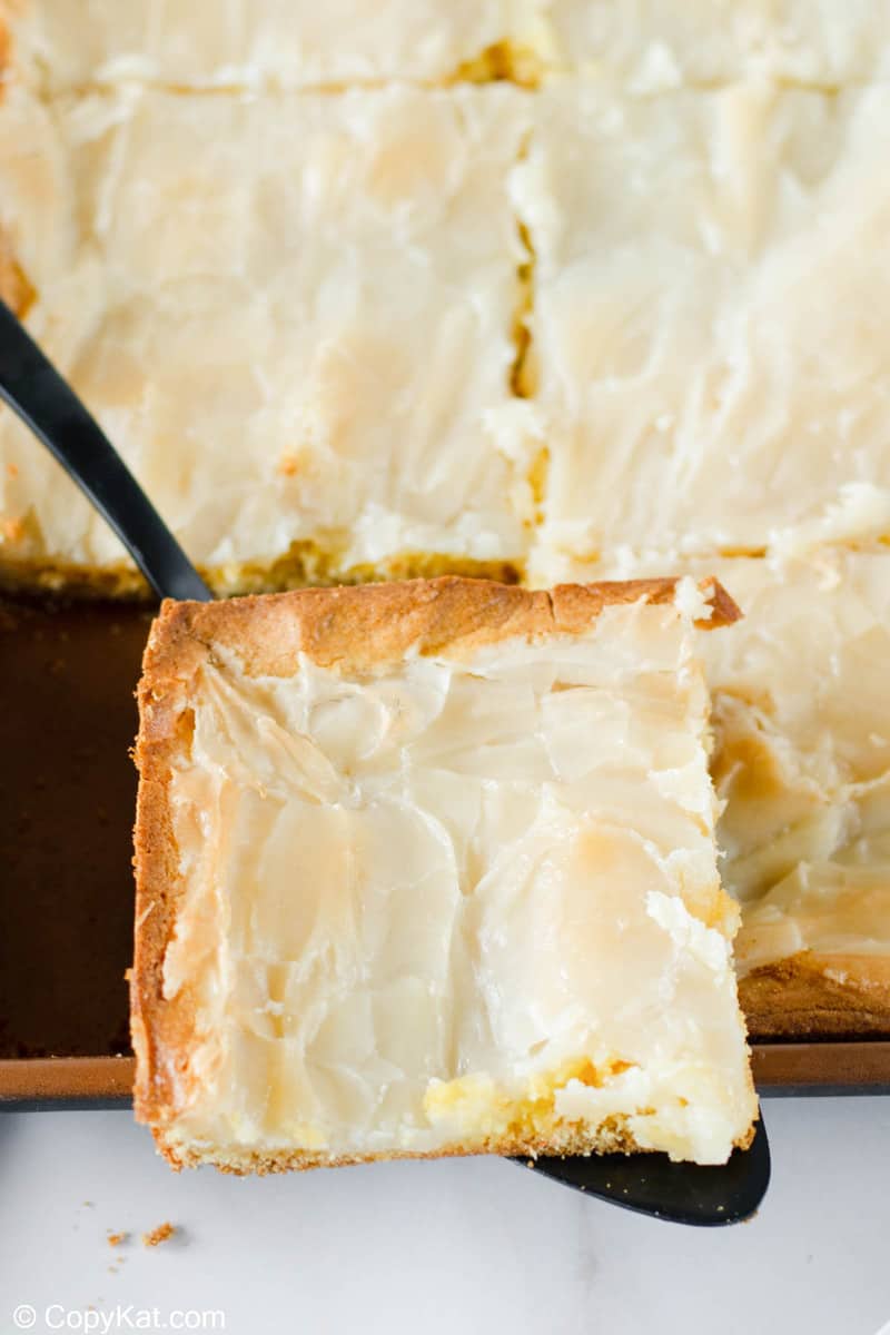 gooey butter cake slice on a cake server over the cake.