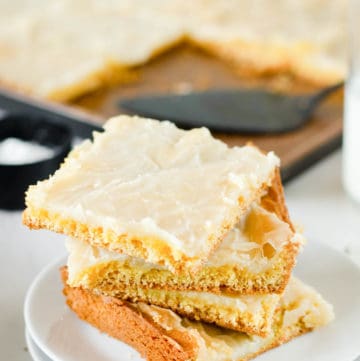 four gooey butter cake slices on a plate in front of the cake in a pan.