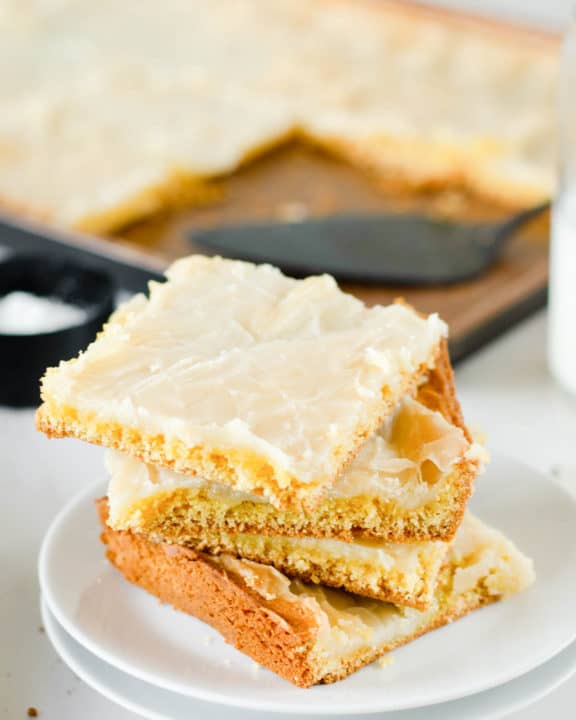 four gooey butter cake slices on a plate in front of the cake in a pan.