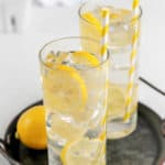 two glasses of homemade lemonade with lemon slices on a tray.