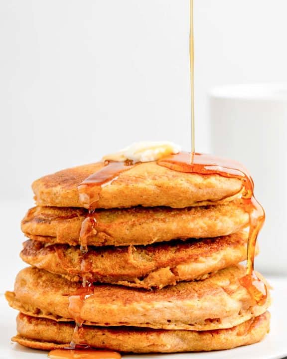 a stack of homemade IHOP pumpkin pancakes with syrup flowing over them.