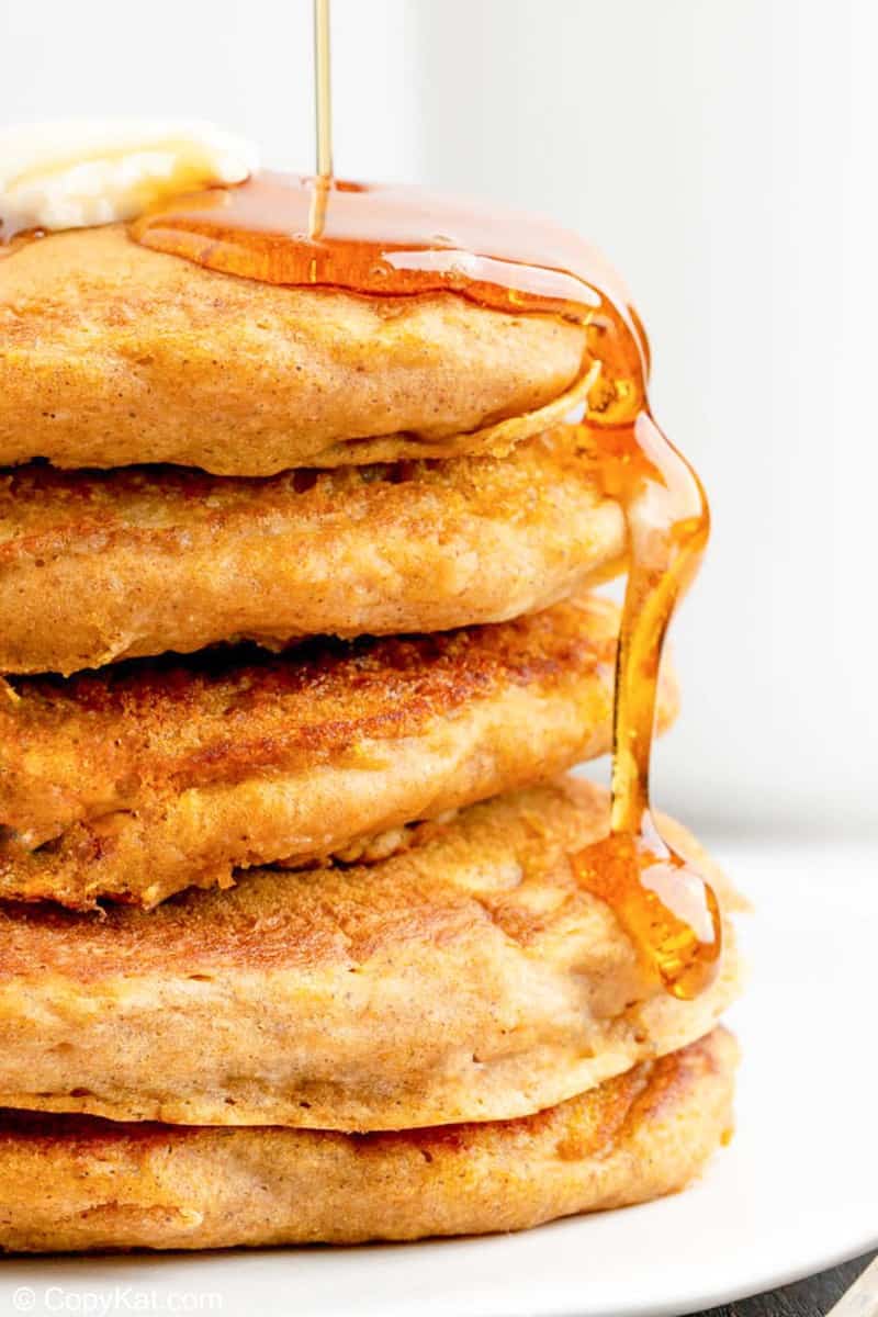 a stack of 5 homemade IHOP pumpkin pancakes with syrup running down the side.