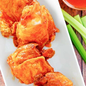 four homemade Wingstop Buffalo chicken thighs, Buffalo sauce, and celery sticks.