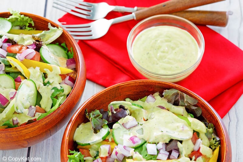 homemade Chick Fil A avocado lime ranch dressing in a bowl and on two salads.