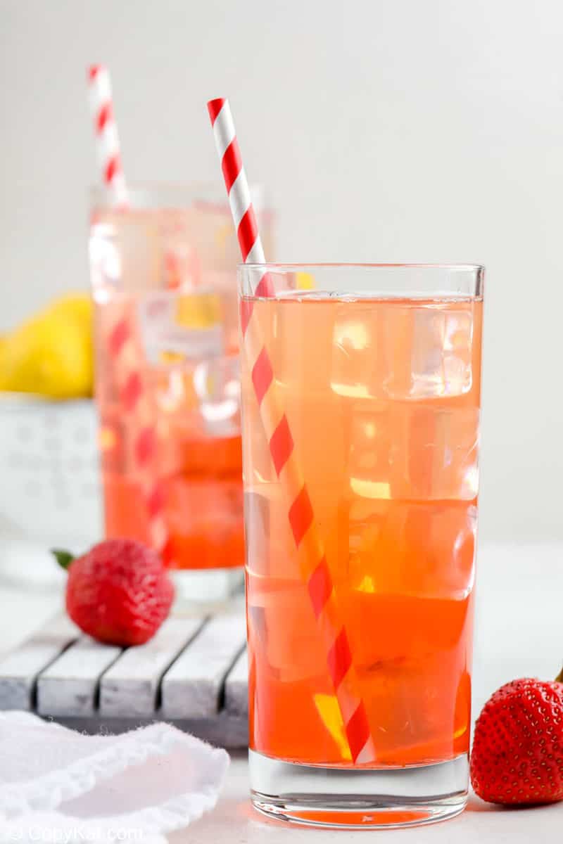 two glasses of homemade Sonic strawberry lemonade, fresh strawberries and lemons.