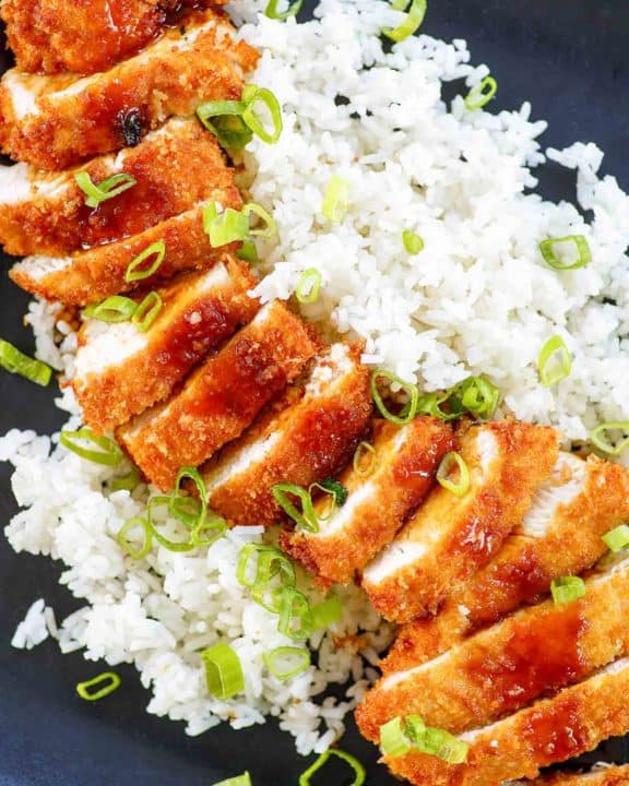sliced chicken katsu with tonkatsu sauce and rice on a platter.
