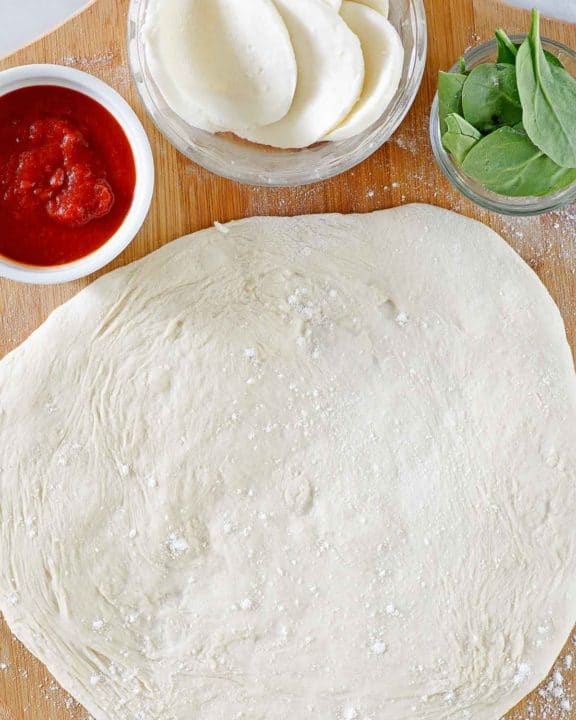 overhead view of homemade pizza dough rolled out on a pizza peel.