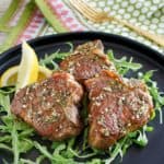 three pan seared lamb chops on a plate.