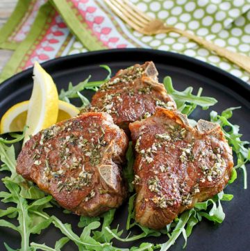 three pan seared lamb chops on a plate.
