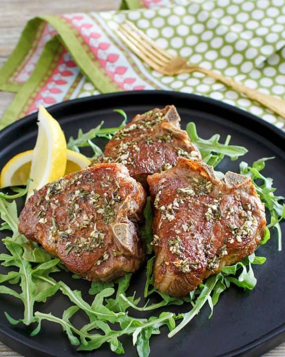 three pan seared lamb chops on a plate.