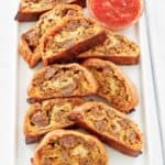 breakfast sausage roll slices and picante sauce on a platter.