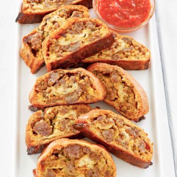 breakfast sausage roll slices and picante sauce on a platter.