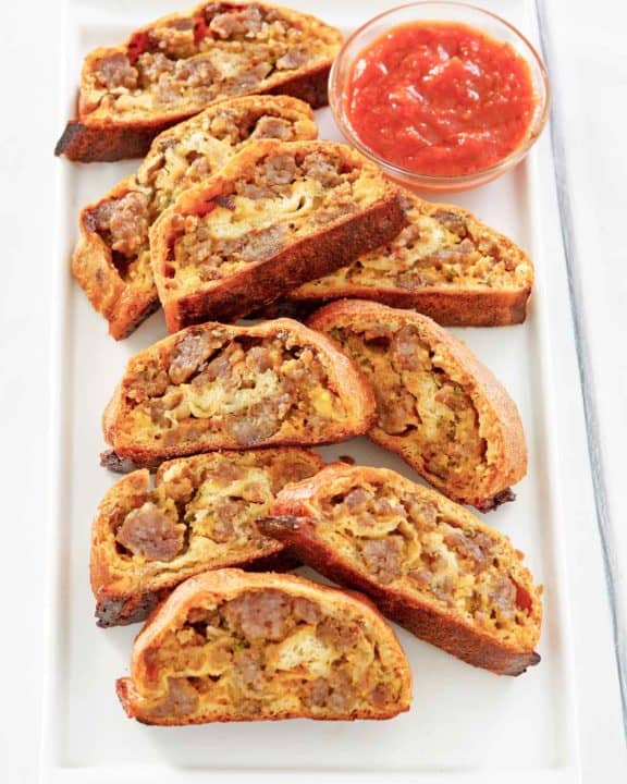 breakfast sausage roll slices and picante sauce on a platter.