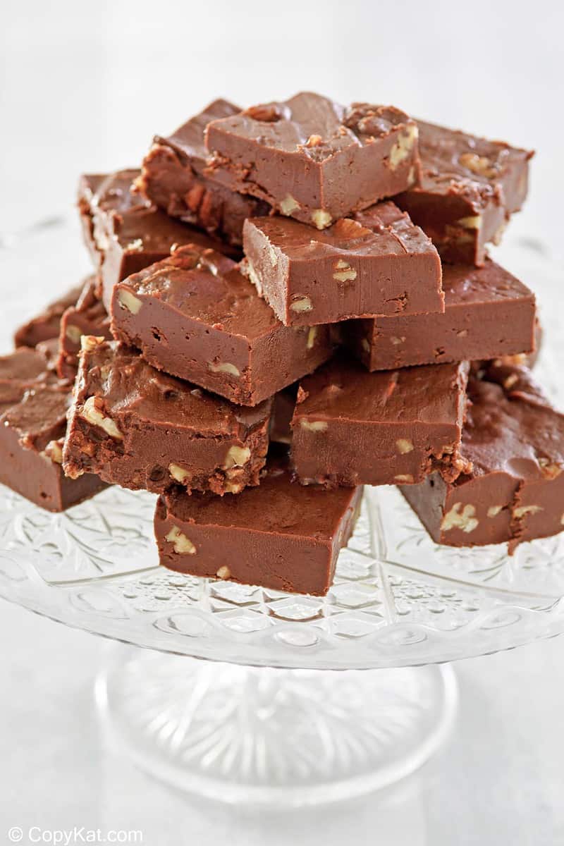 homemade See's chocolate fudge with nuts on a cake stand.