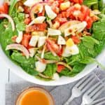 overhead view of spinach salad and a bowl of hot bacon dressing.