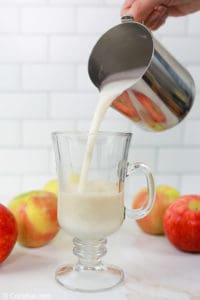 pouring frothed milk into a mug.