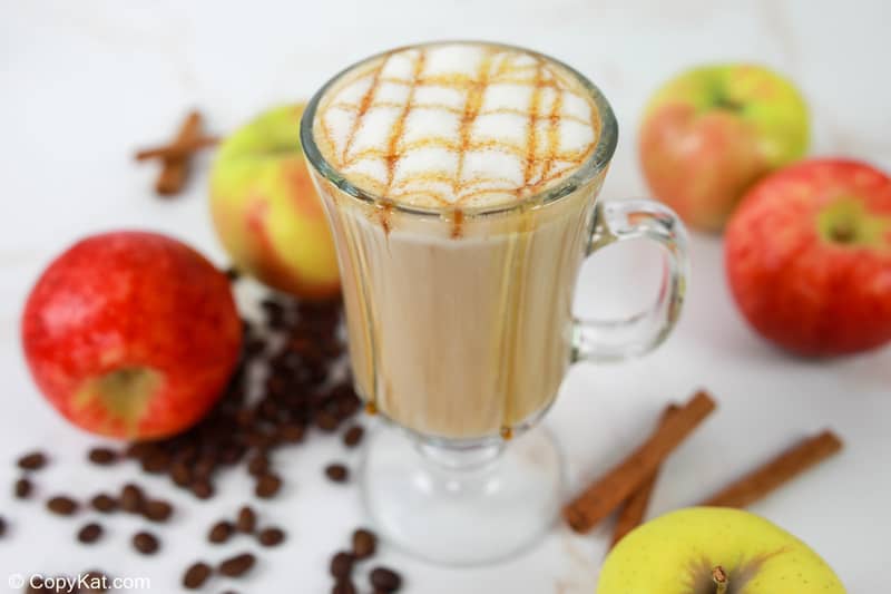 homemade Starbucks apple crisp macchiato, apples, and cinnamon sticks.