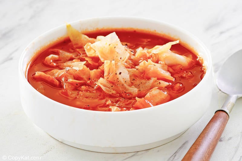 a bowl of cabbage soup and a spoon.
