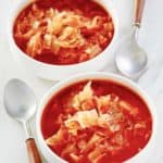 two bowls of cabbage soup and two spoons.