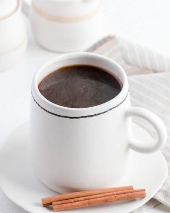 cinnamon coffee, cinnamon sticks, and cream in a small pitcher.
