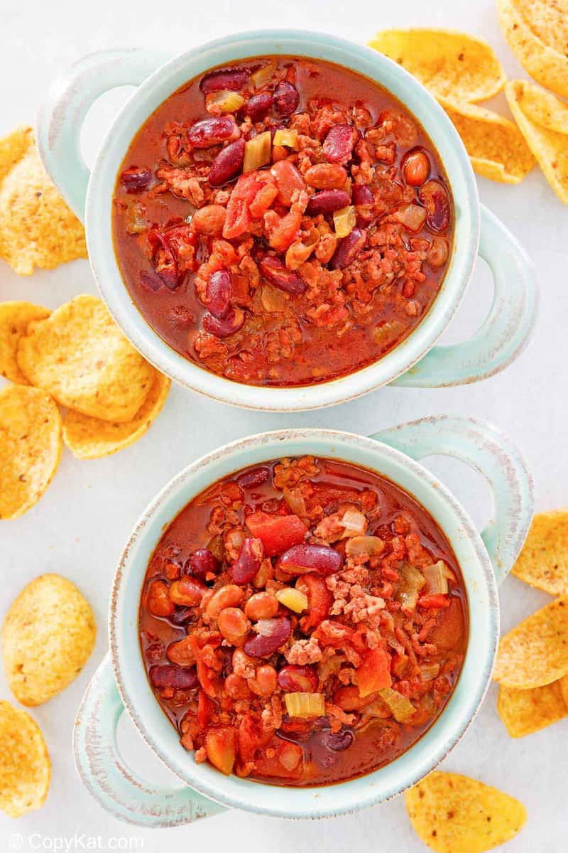 overhead view of two bowls of crockpot chili and corn chips.