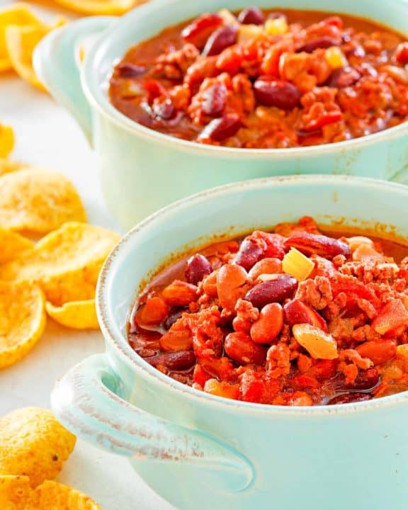 two bowls of crockpot chili and corn chips.
