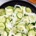 cucumber onion salad in a large black bowl.