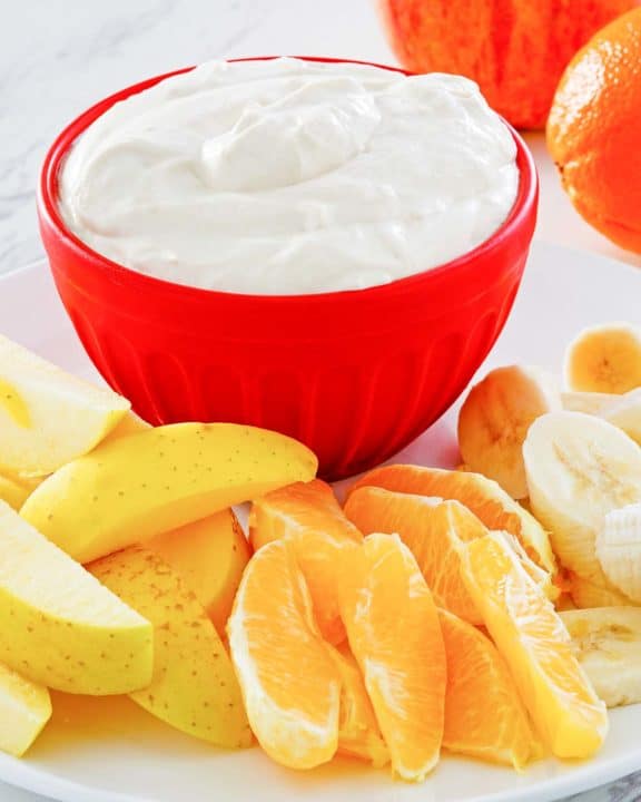 fruit dip in a bowl and various fresh fruit next to it.