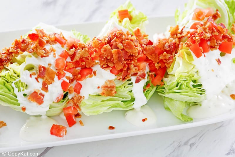 three servings of classic wedge salad on a platter.