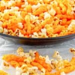 a bowl of homemade Cheetos popcorn and some of it in front on parchment paper.