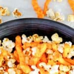 homemade Cheetos Popcorn in a bowl and scattered next to it.