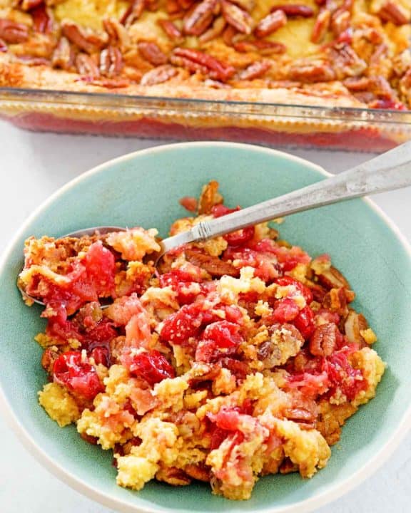 cherry pineapple dump cake in a baking dish and a serving in a bowl.