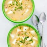 overhead view of corn chowder in two bowls and two spoons.
