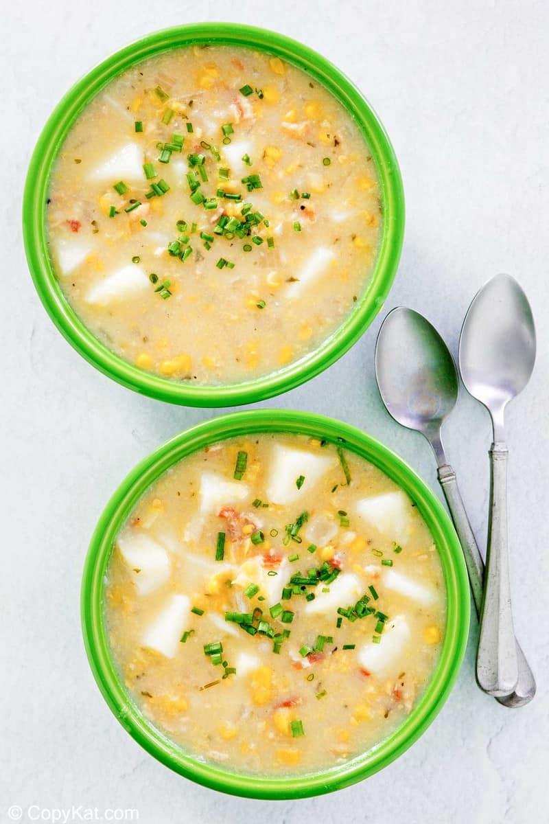 overhead view of corn chowder in two bowls and two spoons.
