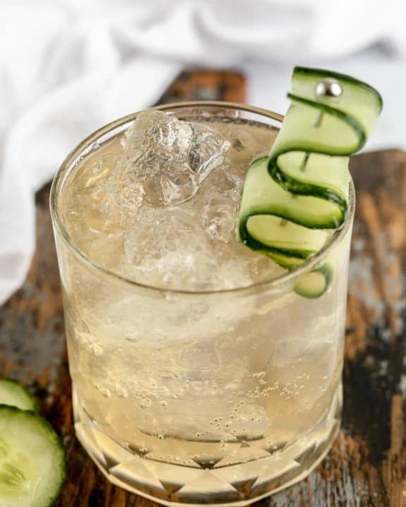 fleur de lis cucumber gin cocktail in a rock glass garnished with cucumber.