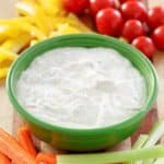 a bowl of dill dip and vegetables on a platter.