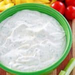 a bowl of dill dip and assorted vegetables.