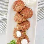 overhead view of chicken croquettes and sour cream on a platter.