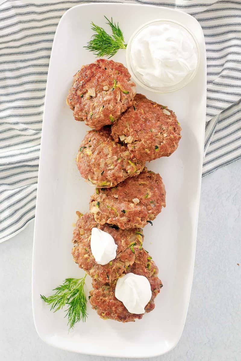 overhead view of chicken croquettes and sour cream on a platter.