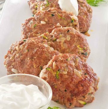 pan-fried chicken croquettes and sour cream on a platter.